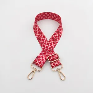 Adjustable red shoulder strap for bags with white floral patterns and gold metal clips