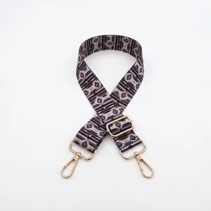 Close-up of geometric pattern crossbody bag strap with adjustable gold metal buckle