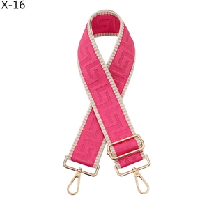 Close-up of wide rose red woven bag strap with golden metal lobster clasps and buckles