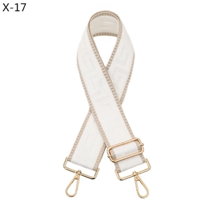 Detail of adjustable cream bag strap with geometric patterns and gold metal lobster clasps