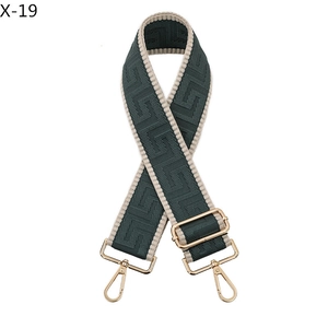 Detail of adjustable bag strap featuring dark green and cream geometric woven pattern