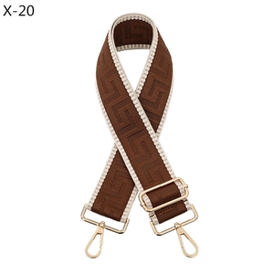 Detail of adjustable wide shoulder strap with brown geometric patterns and gold metal hooks