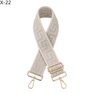 Detail of adjustable wide shoulder strap with beige geometric pattern and gold hardware