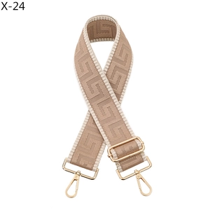 Detailed view of the wide jacquard woven bag strap with golden metal lobster clasps