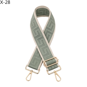 Detail of adjustable woven bag strap with green geometric jacquard and gold hardware