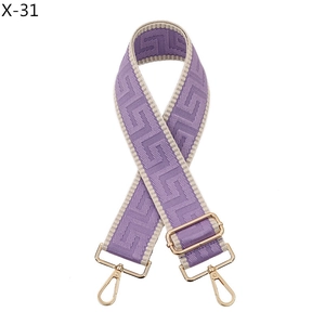 Detail view of purple jacquard geometric bag strap with polished light gold hooks