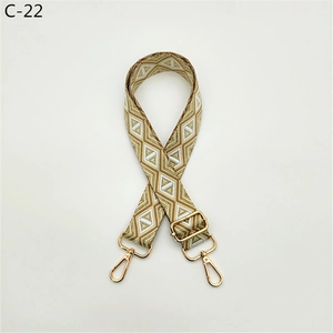 Detail of adjustable geometric diamond pattern bag strap with gold metal buckles