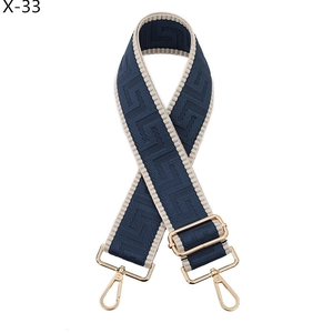 Close-up of geometric woven shoulder strap in navy blue with gold lobster clasps