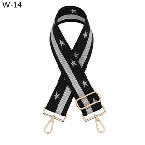 Detail view of adjustable black star pattern bag strap with gold metal lobster clasps