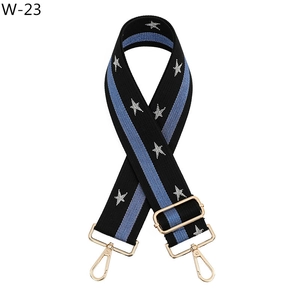Detailed view of adjustable star pattern bag strap with gold metal buckles and hooks