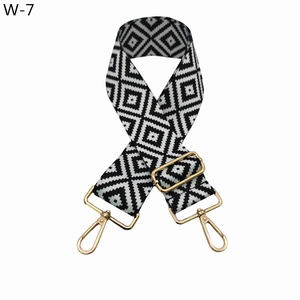 Close-up of black and white geometric pattern woven bag strap with gold metal hooks