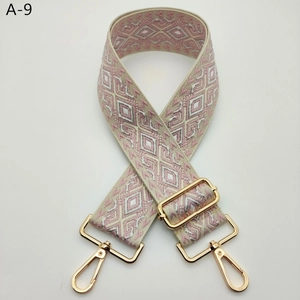 Detailed close-up of wide jacquard bag strap with geometric rhombus pattern and gold metal hooks