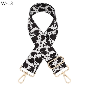 Detail of adjustable polyester bag strap featuring cow print and gold metal buckles