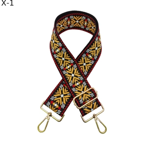 Close-up of ethnic woven handbag strap featuring red geometric patterns and gold lobster clasps