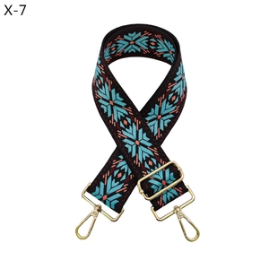 Close-up of ethnic woven bag strap with geometric snowflake pattern and gold metal hooks