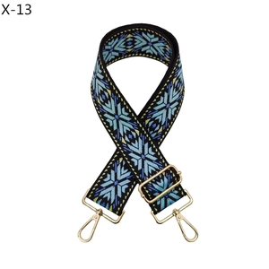 Close-up of geometric ethnic embroidery on adjustable handbag strap with gold metal hooks