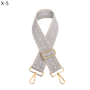 Detail view of woven grey and white diamond pattern bag strap with gold metal hooks