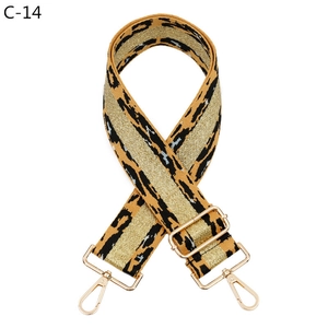 Close-up of wide leopard print bag strap with golden metal hooks and buckles