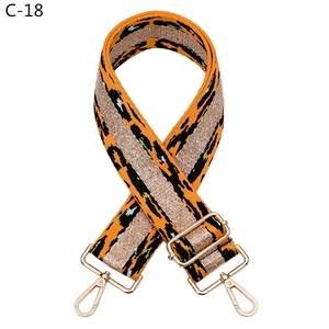 Close-up of leopard print bag strap with orange weaving and golden metal hardware buckles