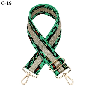 Detail of adjustable wide woven leopard pattern shoulder strap with gold metal buckles