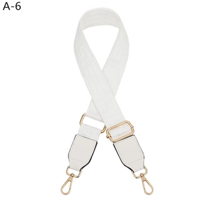 Detail of white Greek key pattern woven bag strap with golden lobster clasp and hardware