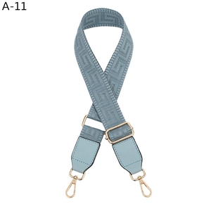 Close-up of light blue geometric jacquard bag strap with gold metal hooks and leather trim