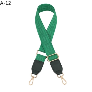 Close-up of green woven shoulder strap with Greek key pattern and gold metal hooks