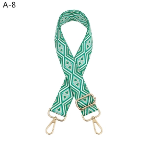 Macro shot of adjustable green diamond pattern woven bag strap with gold metal hardware hooks