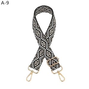 Close-up of woven geometric diamond pattern bag strap with gold metal lobster clasps