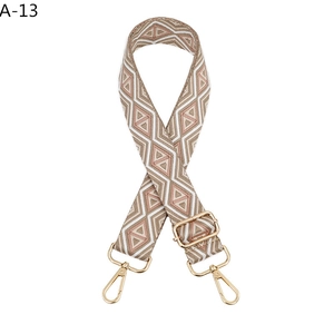 Detail of adjustable woven shoulder strap with geometric diamond pattern and gold metal hooks