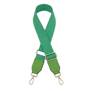 Detail view of grass green canvas bag strap with leather ends and gold metal hooks