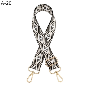 Detail of adjustable black and white geometric woven bag strap with gold metal hooks