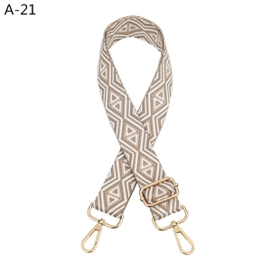 Detail of adjustable woven bag strap with beige geometric pattern and gold swivel hooks