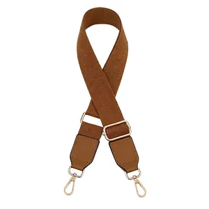 Close-up of brown woven bag strap with adjustable gold buckle and rotating metal hooks