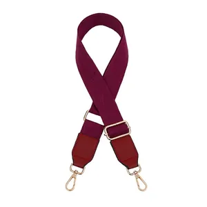 Detail of adjustable wine red canvas shoulder strap with gold metal lobster clasps and buckles