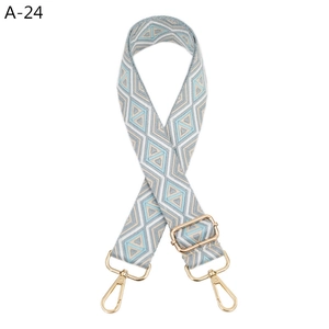 Close-up of geometric woven purse strap with light blue pattern and gold metal hooks