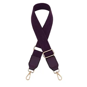 Detail of dark purple adjustable canvas bag strap with leather ends and golden buckles