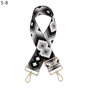 Adjustable wide woven bag strap with black and white geometric diamond pattern and gold clasps