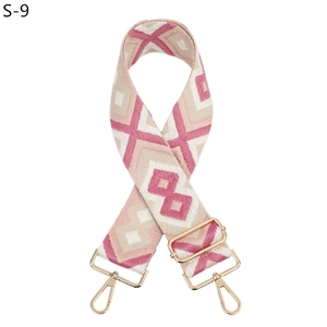 Detail view of pink and beige geometric woven shoulder strap with gold metal hooks