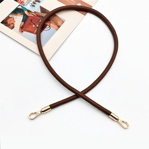 Detail of dark brown PU leather handbag strap with polished golden metal clasps