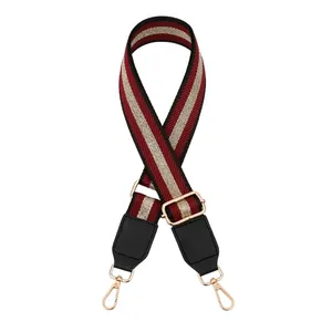 Close-up of adjustable striped handbag strap with gold metal hooks and black leather ends