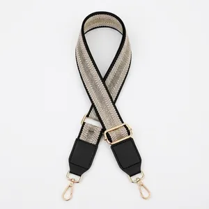 Adjustable woven shoulder strap with black, white, and silver stripes and gold hooks