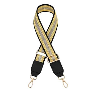 Close-up of yellow and black striped fabric bag strap with golden metal lobster clasps