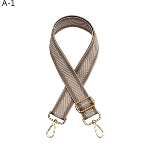 Close-up of khaki chevron bag strap with silver thread and golden metal lobster clasps