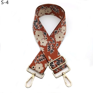 Détail d'une bandoulière rétro tissée rouge brique avec motif floral et crochets dorés