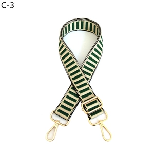 Close-up of adjustable green and gold striped woven bag strap with gold lobster clasps