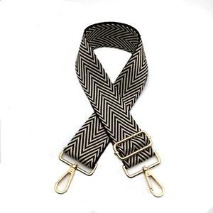 Détail d'une large sangle réglable à chevrons noir et blanc avec boucles en métal doré