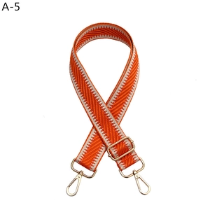 Detail of adjustable orange and white herringbone strap with gold metal lobster clasps