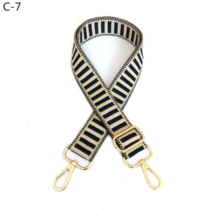 Close-up of adjustable navy blue and cream striped woven bag strap with gold metal hardware