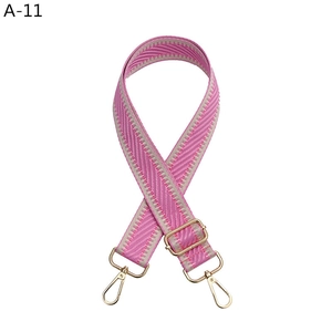 Detail of adjustable pink and beige woven bag strap with golden metal swivel hooks